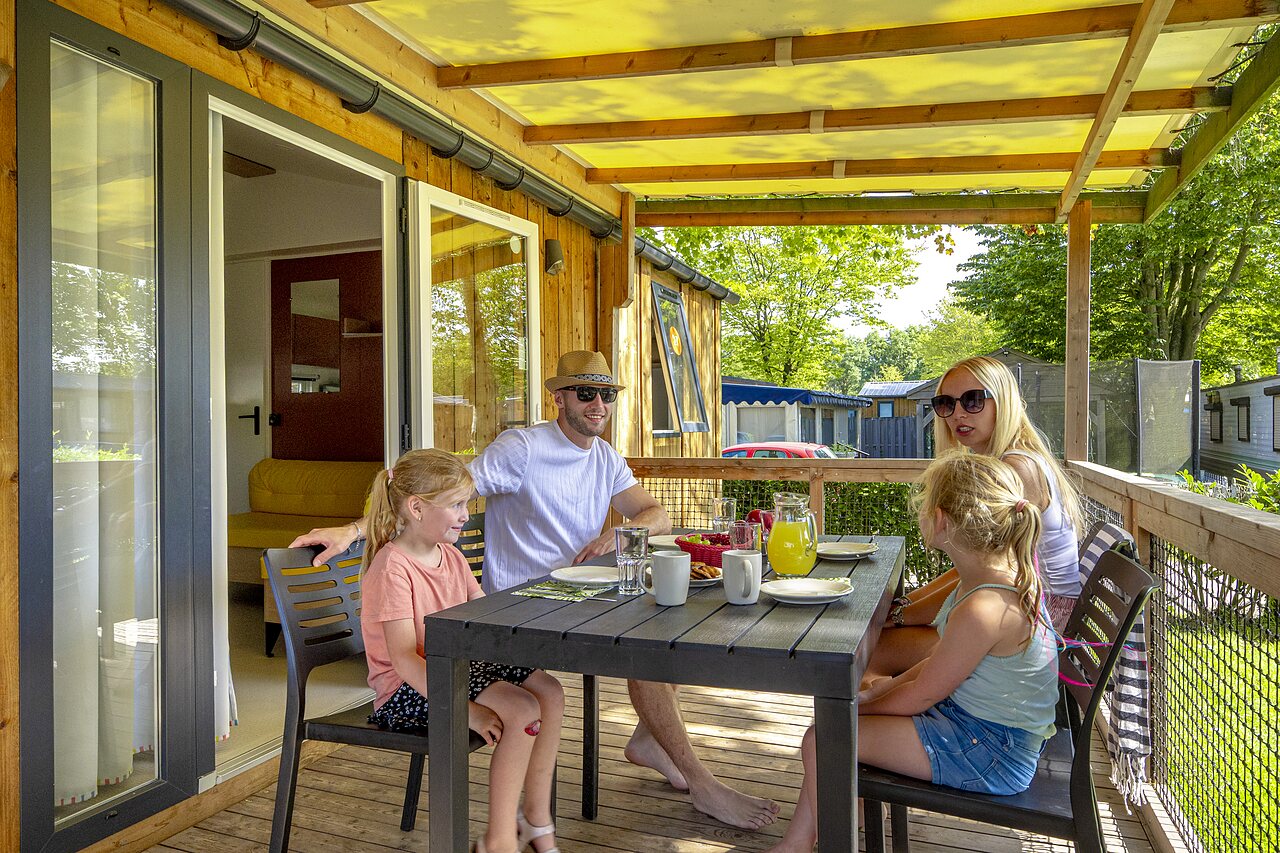 Familie ontbijtend op terras stacaravan bij camping CAPFUN de Wondermolen in Molenschot.