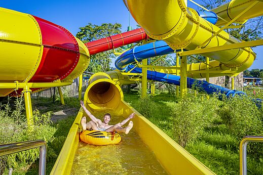 Man op band in gele waterglijbaan op camping CAPFUN de Wondermolen in Molenschot.