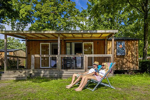 Koppel ontspant voor een stacaravan met terras op camping CAPFUN de Wondermolen in Molenschot.