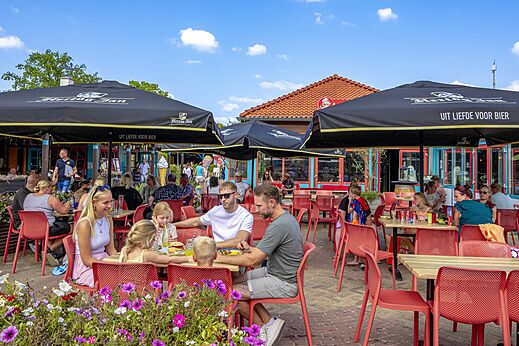 Druk restaurantterras met families en parasols op camping CAPFUN de Wondermolen in Molenschot.
