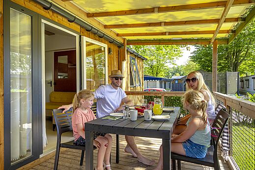 Familie luncht op overdekt terras van een stacaravan op camping CAPFUN de Wondermolen in Molenschot.