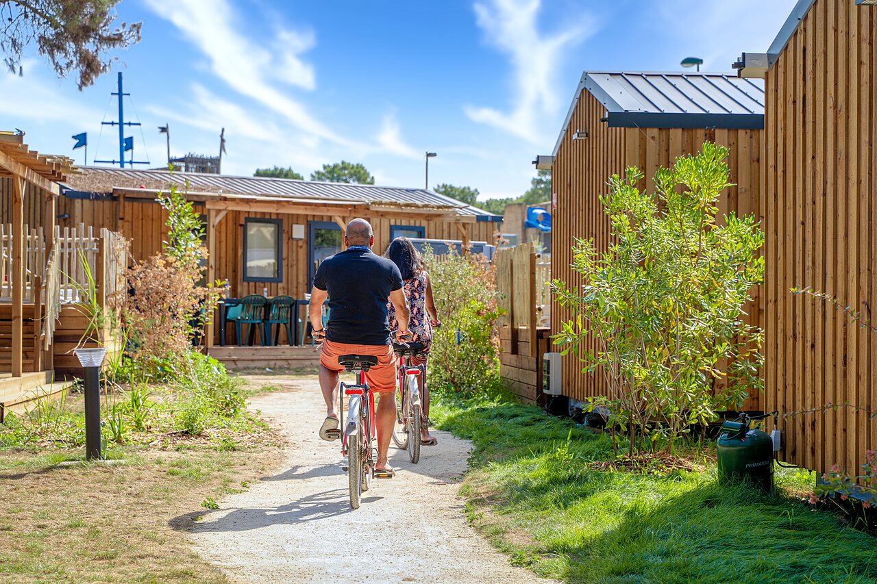 Fietsend stel op pad tussen stacaravans op camping CAPFUN Zagarella in LONGEVILLE SUR MER (85).