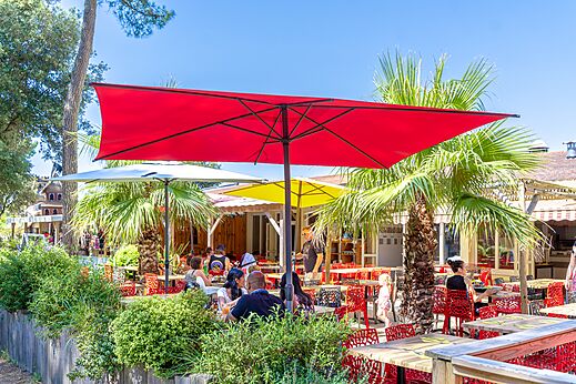 Buitenrestaurantterras met kleurrijke parasols en gasten op camping CAPFUN Zagarella in LONGEVILLE SUR MER (85).