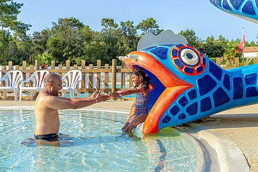 Kind glijdt van visvormige waterglijbaan in zwembad bij CAPFUN Zagarella, LONGEVILLE SUR MER (85).