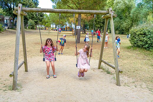 Houten schommel met spelende kinderen op camping CAPFUN Zagarella in LONGEVILLE SUR MER (85).