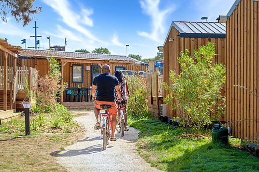 Koppel fietst op pad tussen Mobil-homes op camping CAPFUN Zagarella in LONGEVILLE SUR MER (85).