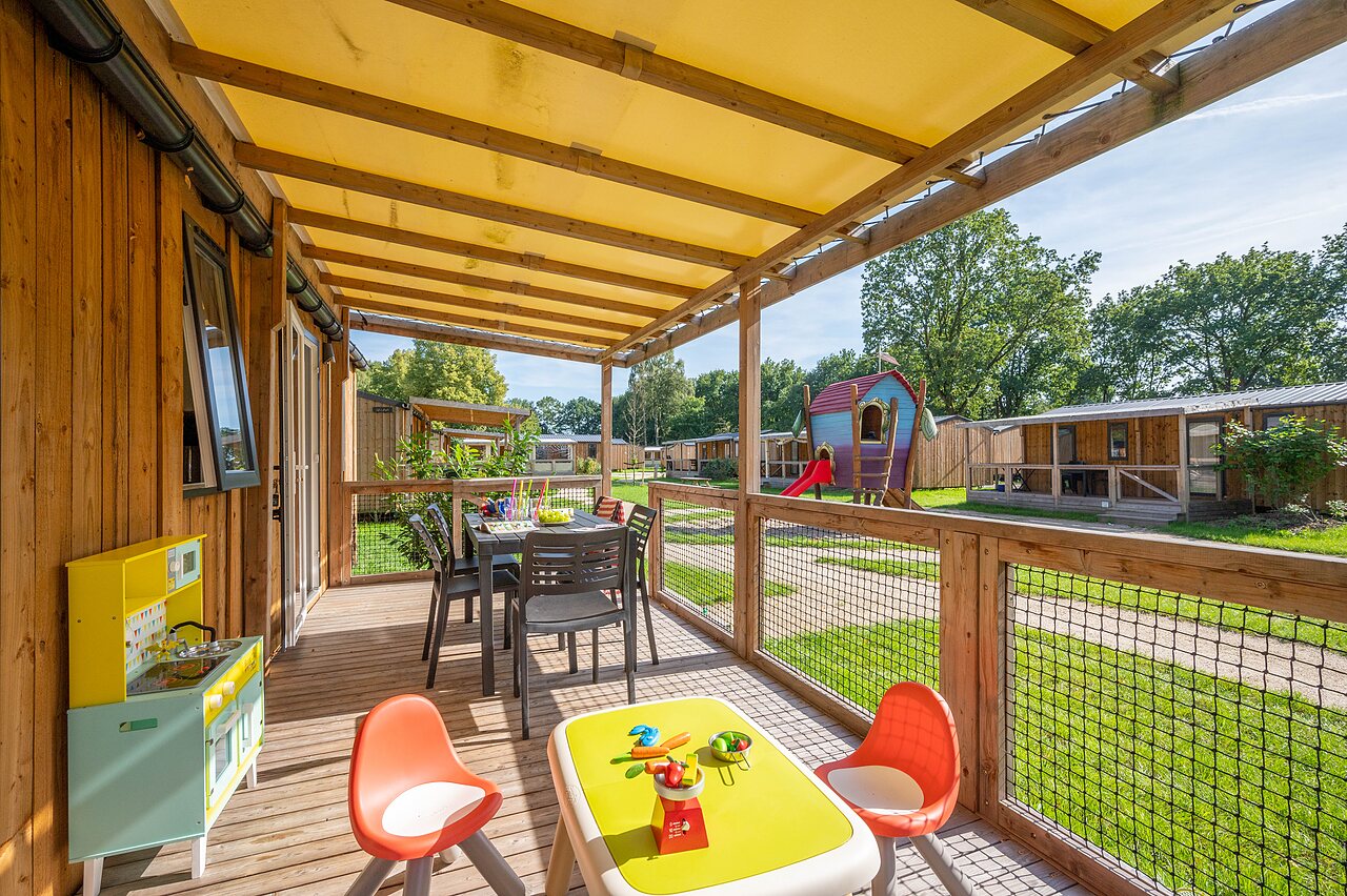 Terras van stacaravan met eettafel en kinderspellen op camping CAPFUN Zeumersehof in Voorthuizen.