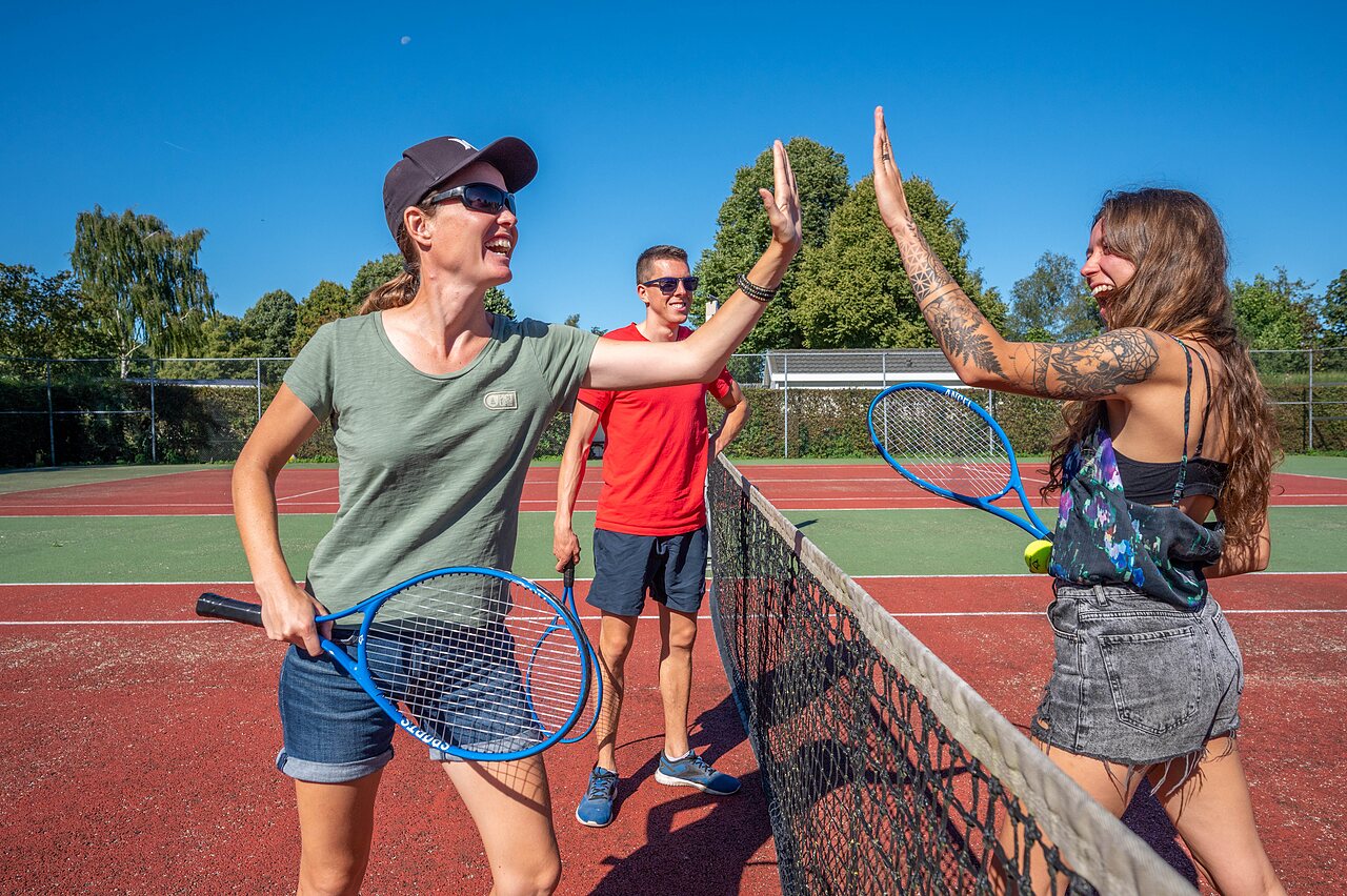 Lachende tennisspelers op het multisportterrein van camping CAPFUN Zeumersehof in Voorthuizen.
