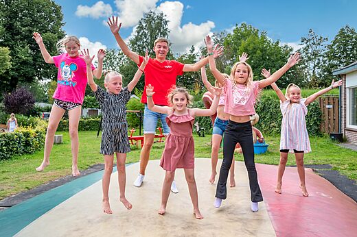 Kinderen en animator springen op een reuzentrampoline op camping CAPFUN Zeumersehof in Voorthuizen.