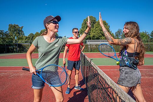 Tennisspelers geven high-five op de tennisbaan bij camping CAPFUN Zeumersehof in Voorthuizen.