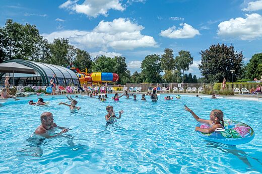 Buitenzwembad met waterglijbanen en zwemmers op camping CAPFUN Zeumersehof in Voorthuizen.