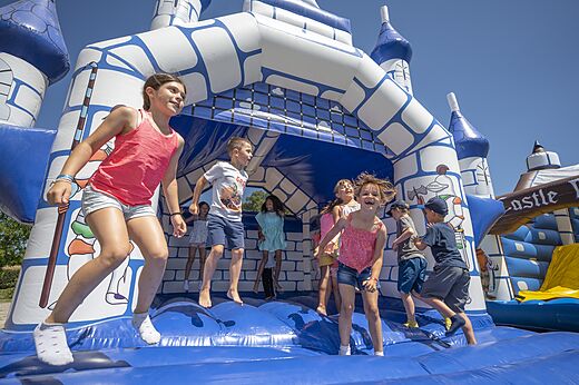 Kinderen springen op een blauw-wit springkasteel op camping CAPFUN Zeumersehof in Voorthuizen.